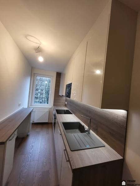 A new kitchen in a 2-room apartment with a wood-patterned floor and modern equipment.