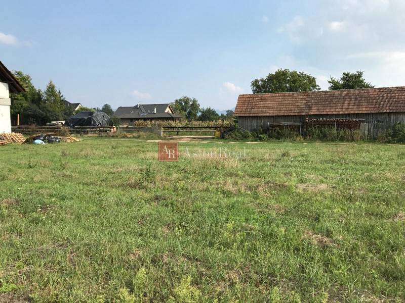 Plots - housing on Poľnohospodárska Street in Trenčín with a grassy area and a farm building.