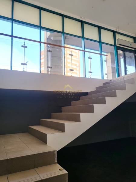 Interior of commercial spaces with glass walls and a staircase.