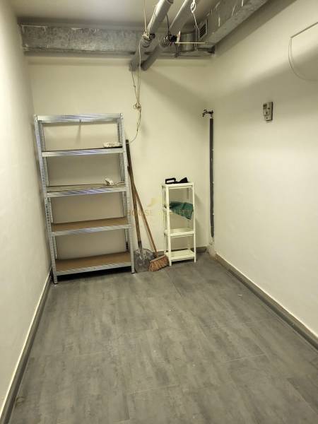 A small warehouse with metal shelves and tools, floor with wooden decor.