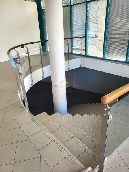 A staircase with glass railing leads to the lower part of the commercial premises.