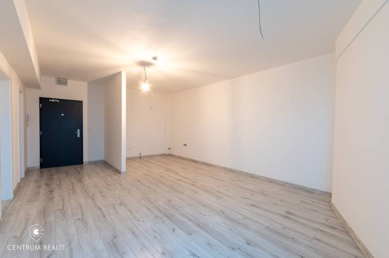 A room in a 2-room apartment with white walls and a floor with a wooden decor.