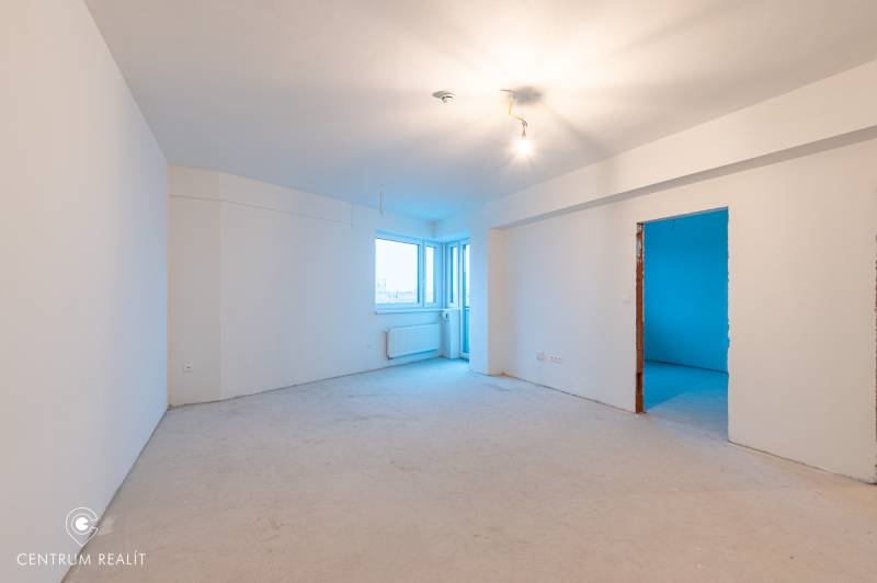 A spacious room in a 2-room apartment with white walls and lighting.