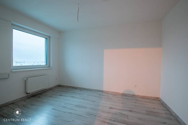 A bright room with a large window and a wooden decor floor in a 2-room apartment.