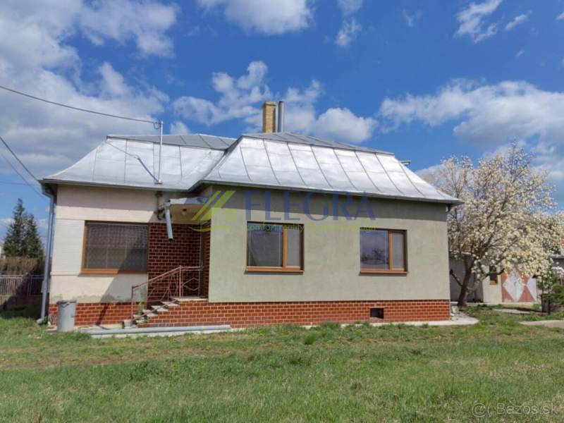 A family house in Veľké Raškovce with a steel roof and basic facade, front garden.
