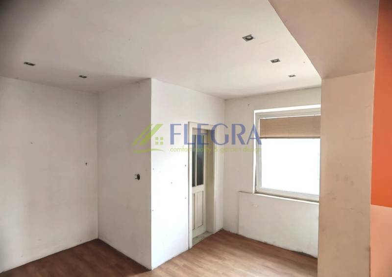 Interior of a family house with white walls, wood-patterned flooring, and a window.