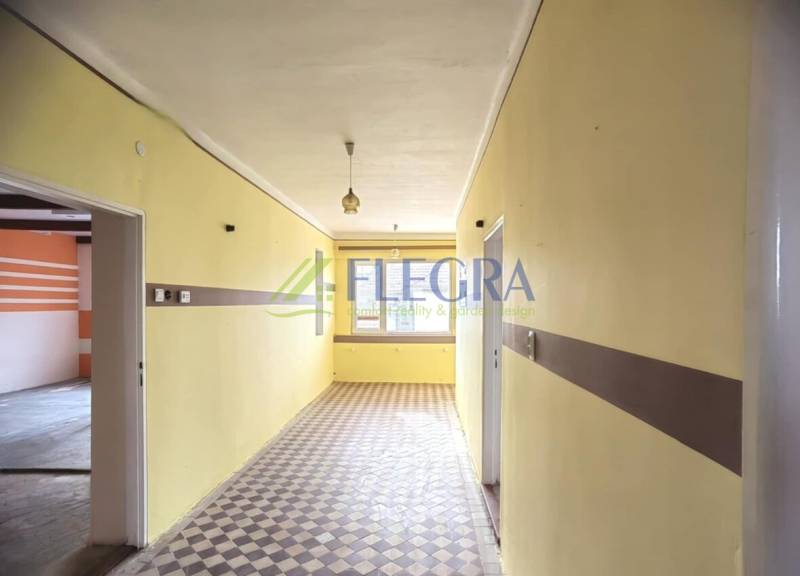 A hallway in a family house with a tiled floor and yellow walls.