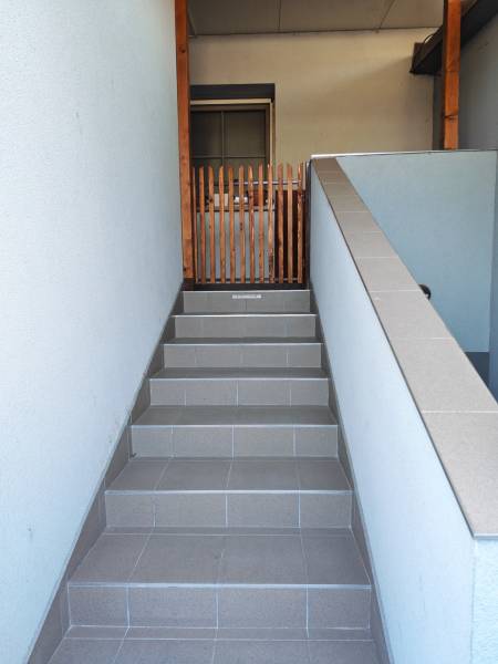 A staircase with ceramic tiles leads to an entrance secured by a wooden gate.
