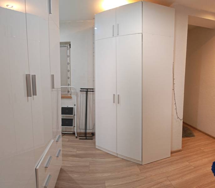 White cabinets in a studio apartment with a wood-patterned floor, room illuminated by a lamp.