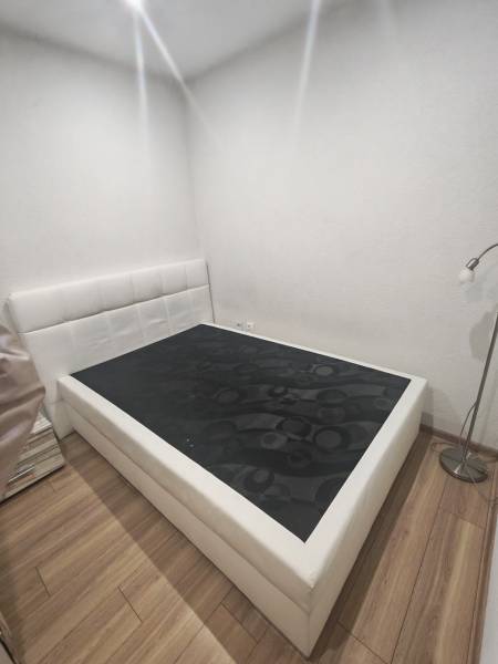 Bedroom with a bed, nightstand, and wooden decor flooring in a studio apartment.