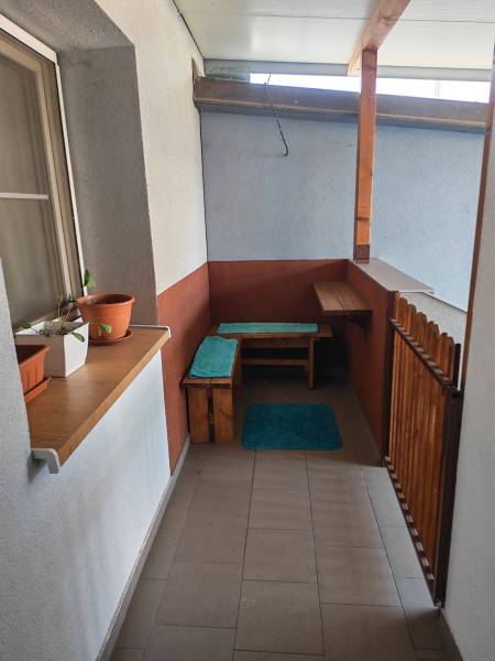 A balcony with wooden furniture and plants in a studio apartment.