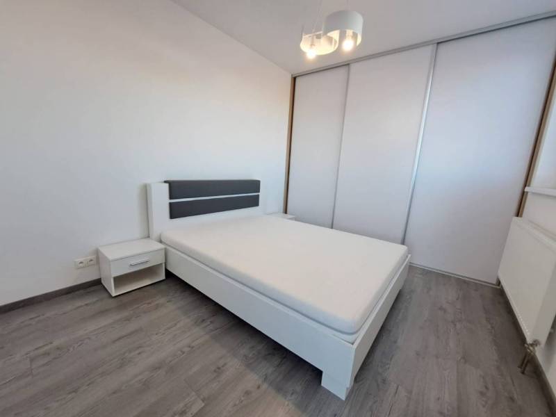 Bedroom with a large bed, nightstand, and sliding wardrobe in a 2-room apartment.