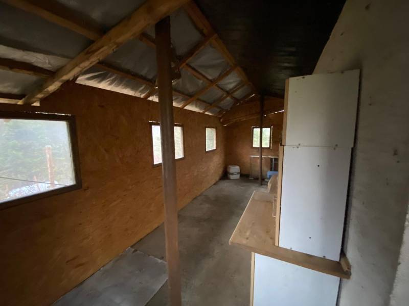 Interior of a cabin with wooden decor and windows, without visible furnishings.