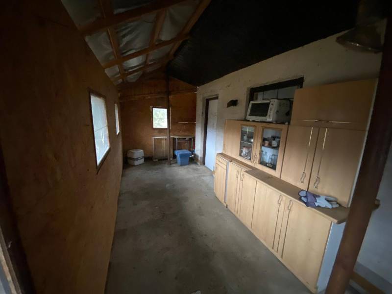The interior of the cottage with simple furniture, a shelving cabinet, and basic kitchen equipment.