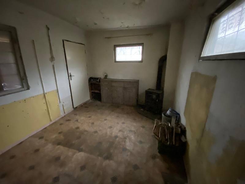 A room in a cottage with wooden decor and a tiled stove.