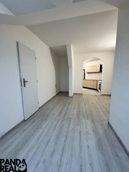 A studio apartment with a wooden decor floor and a kitchen area.