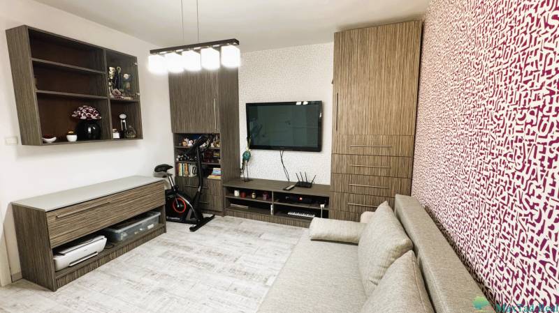 A room in a 3-room apartment with a television, a sofa, and a wooden decor floor.