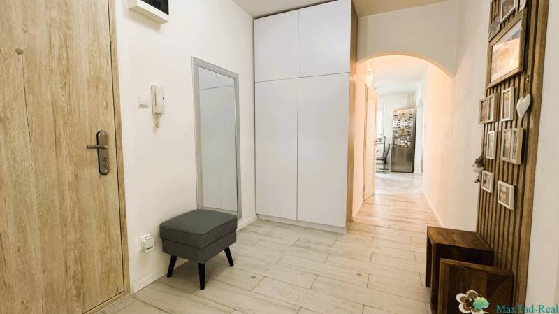 A hallway of a 3-room apartment with a wooden decor floor, a mirror, and storage space.