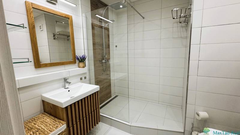 A bathroom in a 3-room apartment with a modern shower and wooden elements.