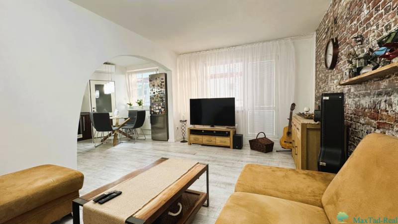 Living room in a three-room apartment with a wooden decor floor and a brick wall.