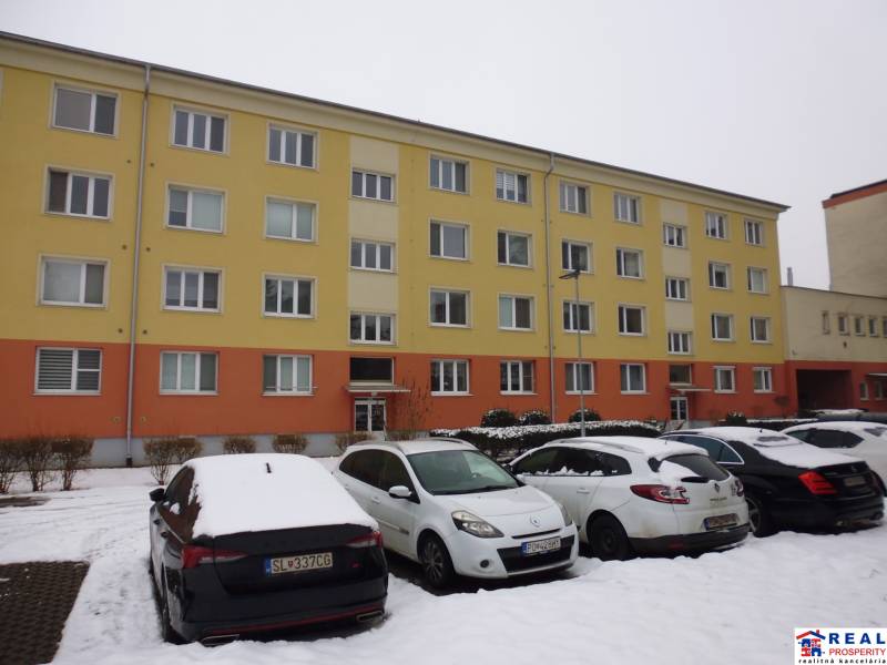 In the snowy city of Prešov on 17th November Street, there is an apartment building with a parking lot.