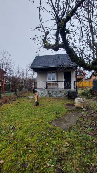 A cottage in Nové Zámky with a grassy garden and trees, simple architecture.