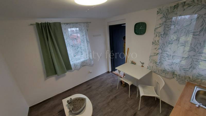 A cottage with a wooden floor decor, curtains, a table, and two white chairs.