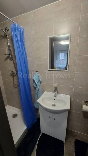 A bathroom in a cabin with a shower, a sink, and a blue curtain.