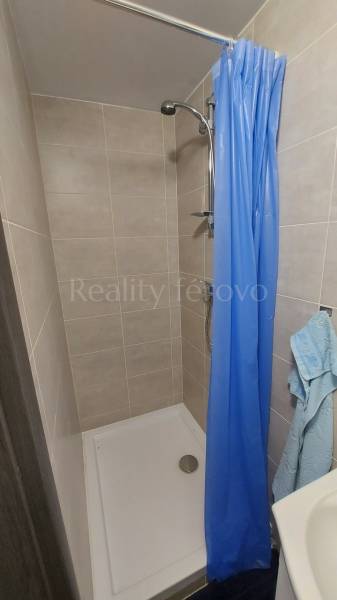 Shower stall with a blue curtain and tiles in a cabin.