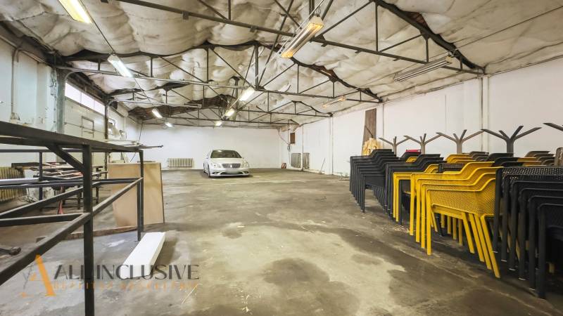 A spacious interior area with a car, chairs, and storage shelves.