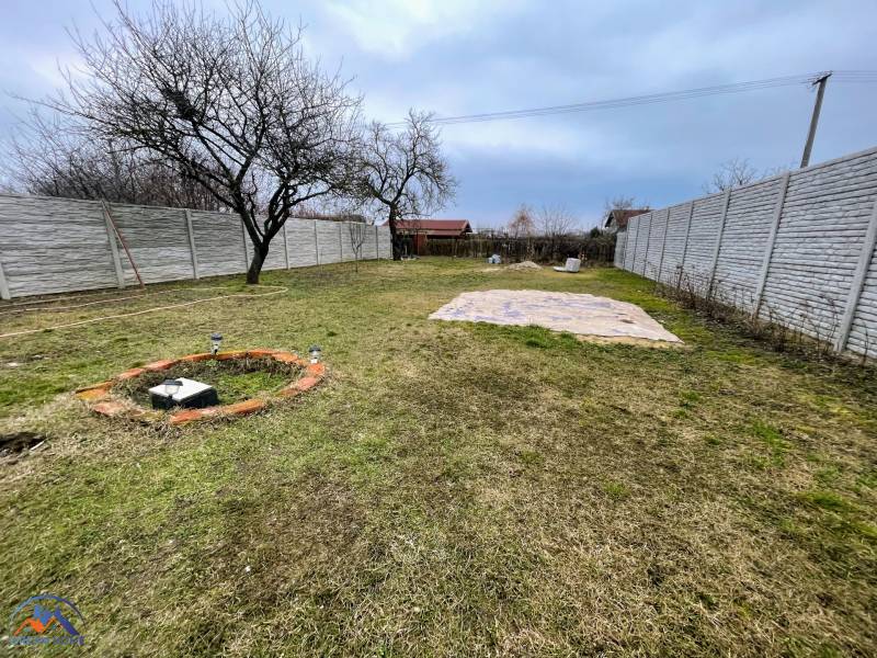 The garden of the cottage in Komárno with fruit trees and a lawn, surrounded by a fence.