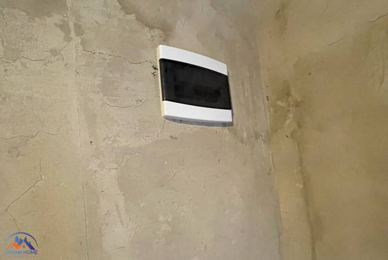 An electrical distribution box on a peeling wall in the interior of a cottage.