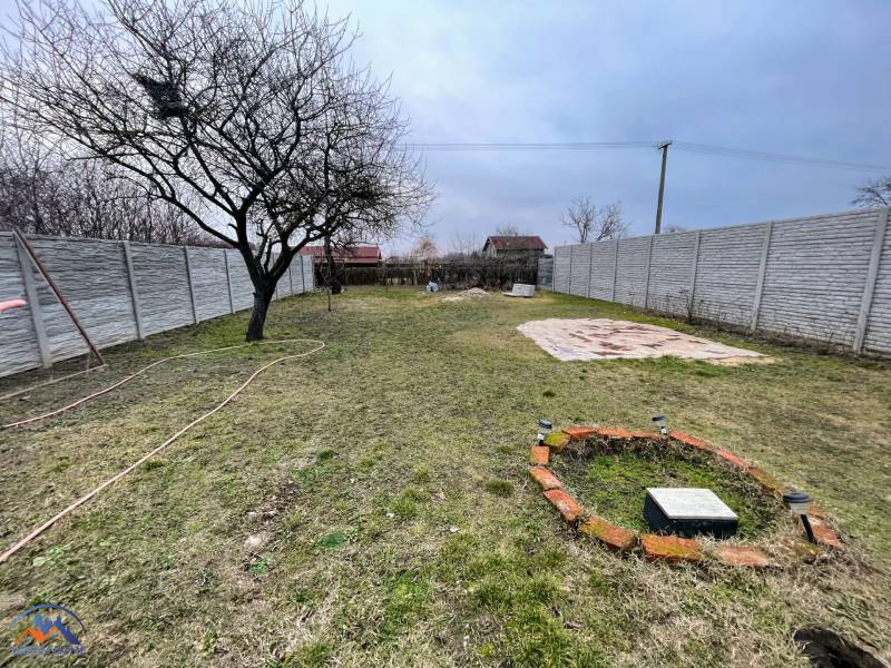 A garden with an unkempt lawn surrounded by a fence near a cottage in Komárno.