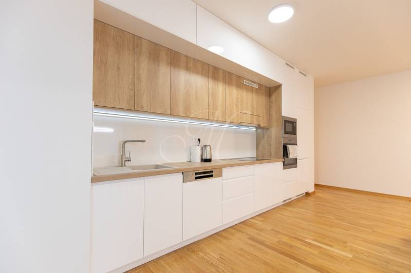 A kitchen in a 3-room apartment with a wooden decor floor and white cabinets.