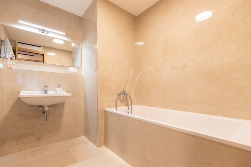Bathroom with a bathtub, sink, and large mirror in a 3-room apartment.