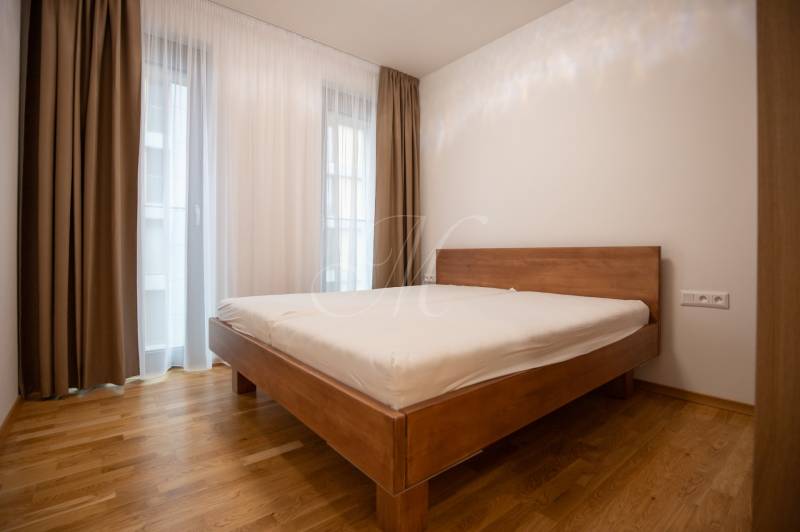 A bedroom with a bed and a wooden decor floor in a 3-room apartment.