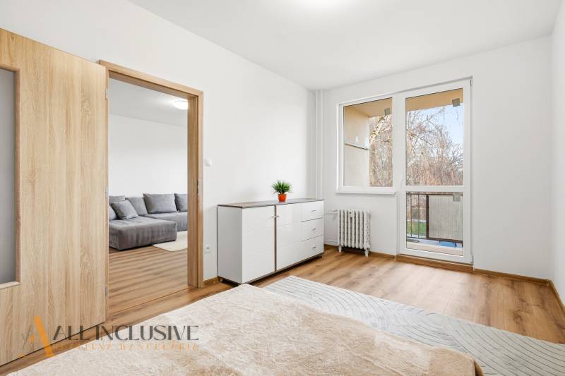 Bedroom in a 3-room apartment with wood-patterned flooring and comfortable furnishings.