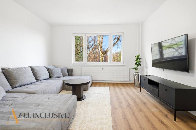 Living room with a large sofa, television, and wooden decor flooring in a 3-room apartment.