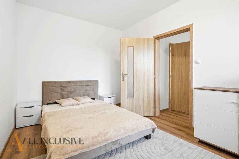 A bedroom in a 3-room apartment with a wooden decor floor, a double bed, and a dresser.