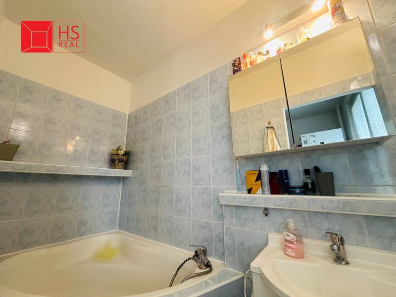 Bathroom in a 3-room apartment, blue tiles, bathtub, mirror cabinet with lighting.