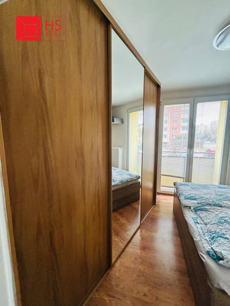 A bedroom in a 3-room apartment with a wooden decor floor and a large built-in wardrobe.
