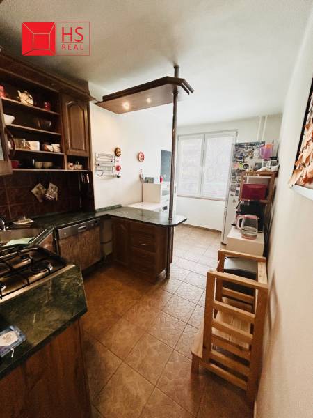 A kitchen in a 3-room apartment with brown furniture and ceramic flooring.