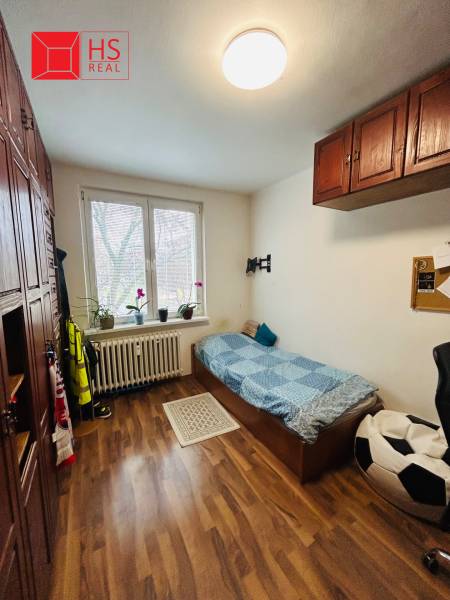 A room in a 3-room apartment with a wooden decor floor and a sofa by the window.