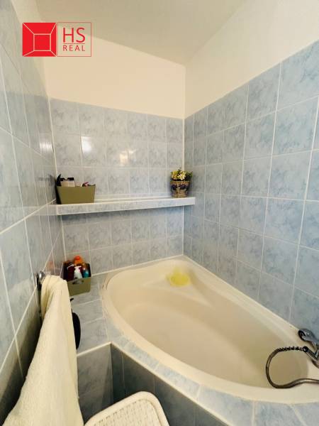 Bathroom with a bathtub with blue tiles in a 3-room apartment, decorations and a towel on the wall.