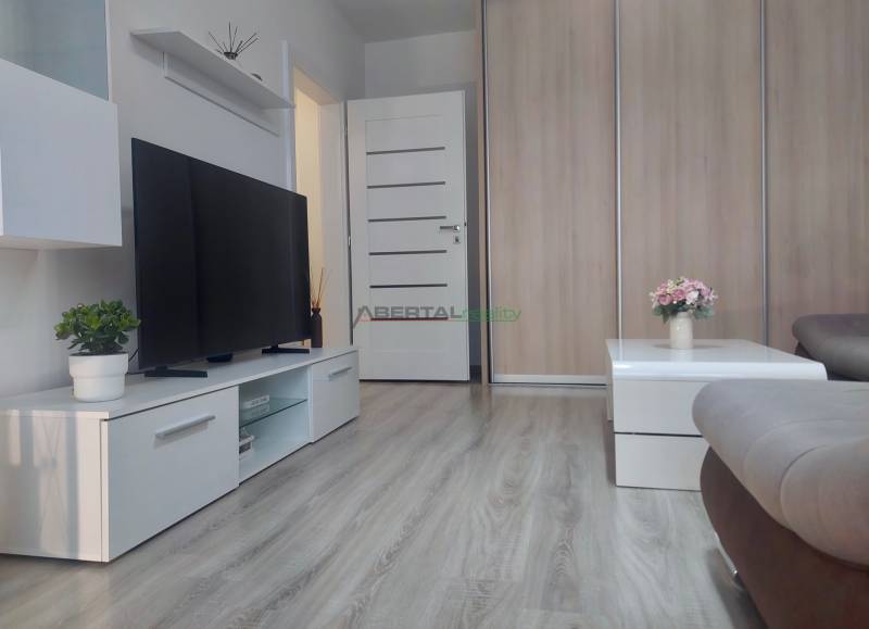 Television, coffee table with flowers, and wooden decor flooring in a 2-room apartment.