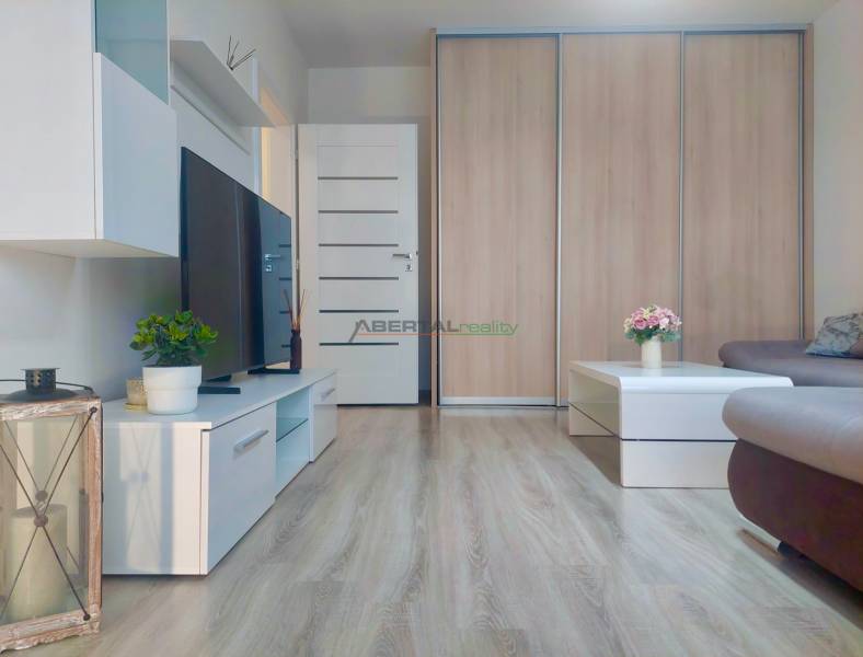 Living room of a two-room apartment with a wooden decor floor and modern furniture.