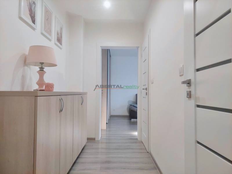 A hallway in a 2-room apartment with a chest of drawers, a lamp, and a wooden decor floor.