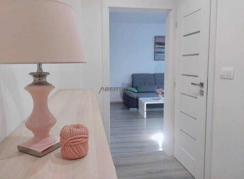 Interior of a 2-room apartment with a view of a gray sofa and a floor with a wooden decor.
