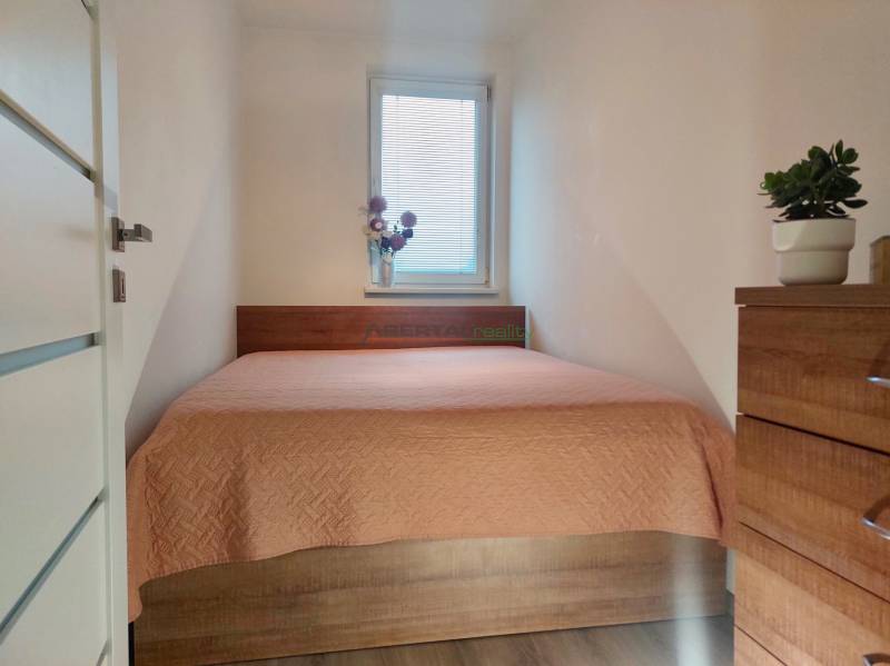 A bedroom in a two-room apartment with a bed and a spacious wooden dresser.