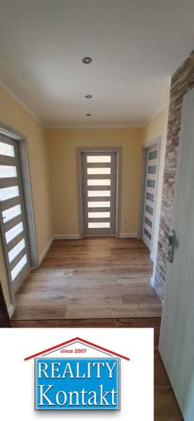 A hallway in a 2-room apartment with a wooden decor floor and light-colored doors.